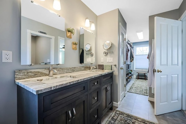 bathroom with a sink, baseboards, double vanity, and tile patterned flooring