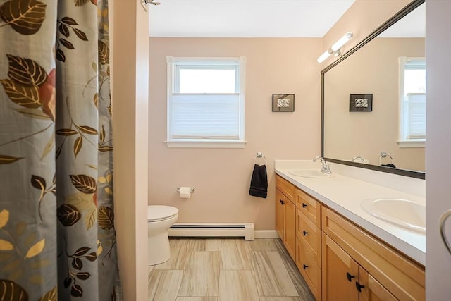 bathroom with double vanity, toilet, baseboard heating, and a sink