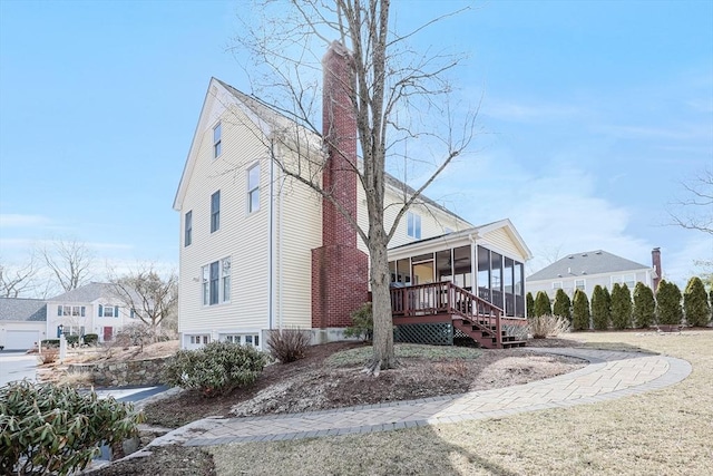 view of side of home featuring a sunroom and a chimney