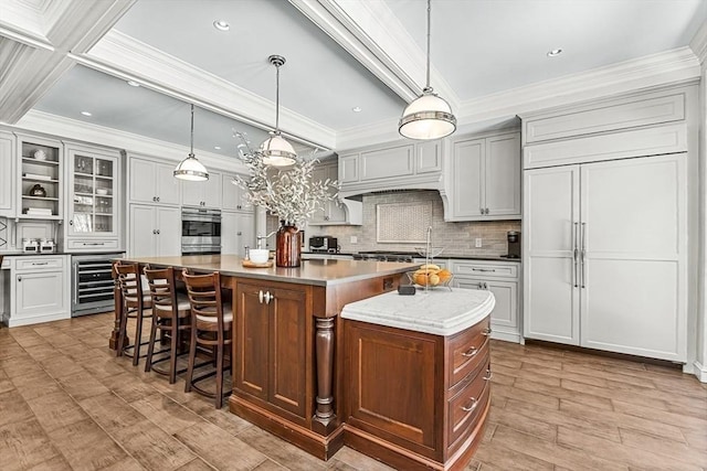 kitchen featuring beverage cooler, a large island, a breakfast bar area, crown molding, and light wood-type flooring