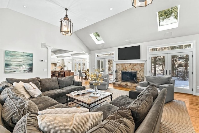 living area with high vaulted ceiling, french doors, a skylight, and wood finished floors