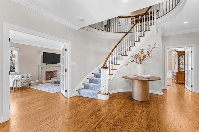 stairway featuring ornamental molding, recessed lighting, a fireplace, and wood finished floors