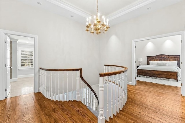 hall with crown molding, recessed lighting, an inviting chandelier, an upstairs landing, and wood finished floors