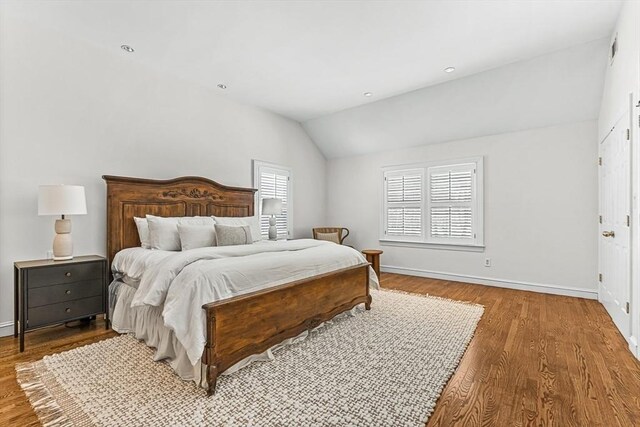 bedroom with lofted ceiling, wood finished floors, and baseboards