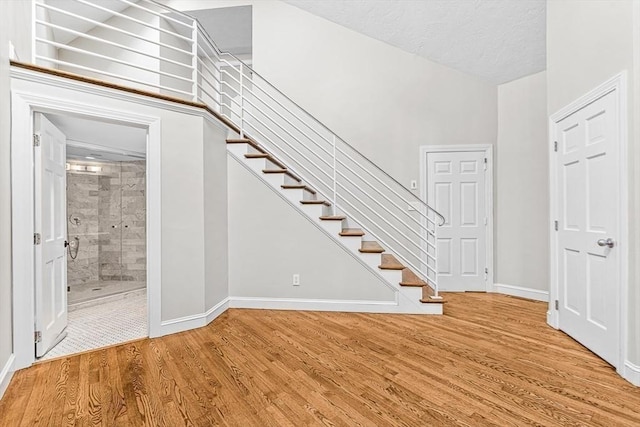 interior space with a textured ceiling, stairway, baseboards, and wood finished floors