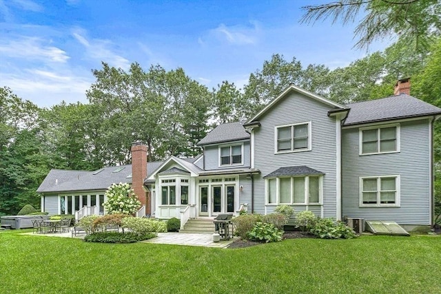 rear view of house with a patio area, a lawn, and a chimney