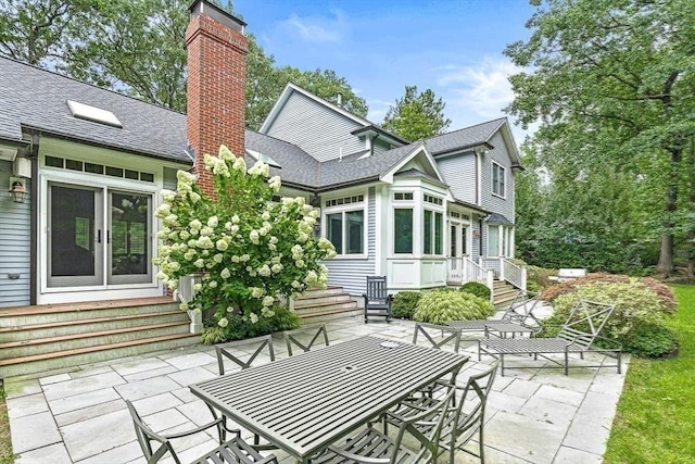 back of property featuring entry steps, french doors, roof with shingles, a chimney, and a patio area