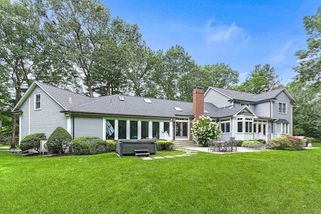 back of property featuring entry steps, a yard, a chimney, a patio area, and a hot tub