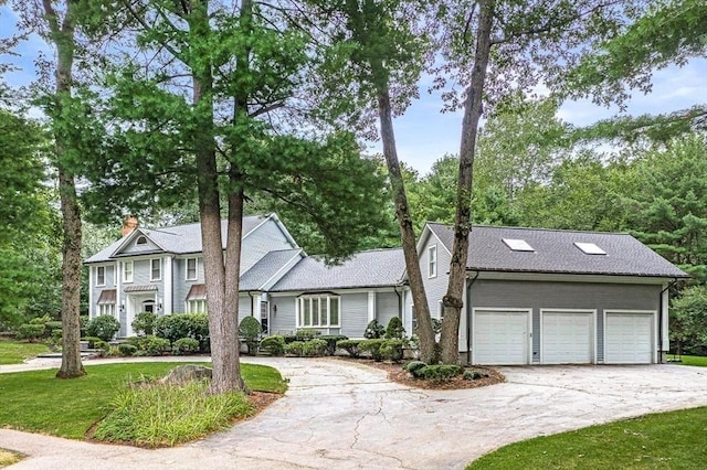 view of front of home featuring driveway, a front lawn, a chimney, and an attached garage