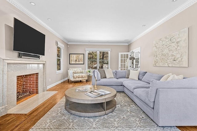 living area featuring baseboards, a premium fireplace, wood finished floors, crown molding, and recessed lighting