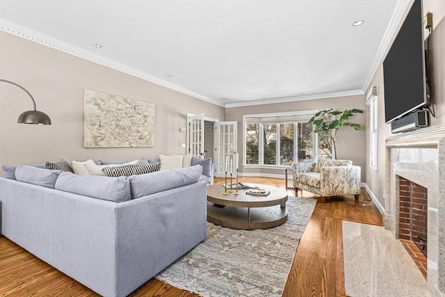 living area featuring ornamental molding, a fireplace, baseboards, and wood finished floors