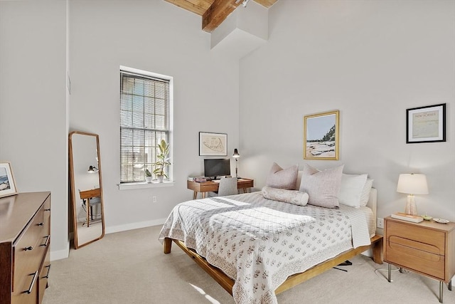 bedroom featuring beamed ceiling, light colored carpet, and baseboards