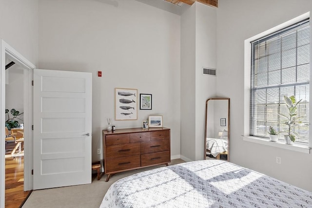 carpeted bedroom with visible vents and a towering ceiling