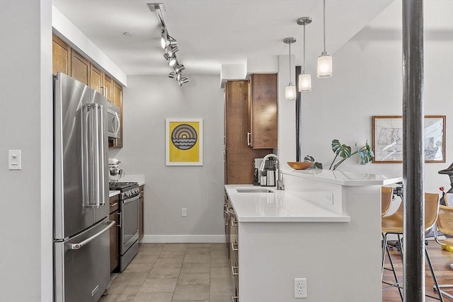 kitchen with a sink, a breakfast bar area, brown cabinetry, stainless steel appliances, and a peninsula