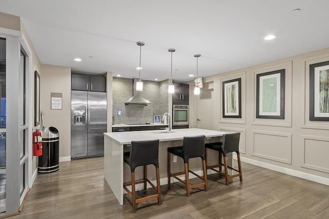 kitchen with decorative backsplash, light countertops, a sink, light wood-style flooring, and stainless steel appliances