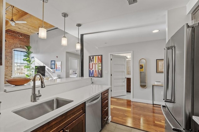 kitchen featuring a ceiling fan, hanging light fixtures, light countertops, a sink, and stainless steel appliances