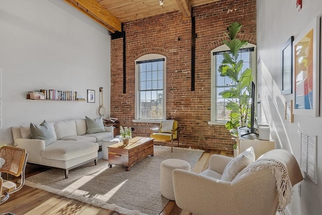 sitting room with a high ceiling, beam ceiling, brick wall, wooden ceiling, and wood finished floors