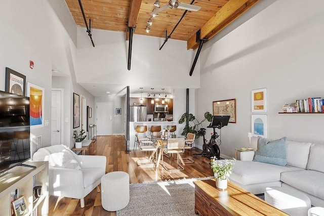 living area with wood ceiling, visible vents, wood finished floors, beamed ceiling, and a high ceiling