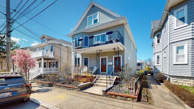view of front of home featuring a balcony, a porch, and uncovered parking