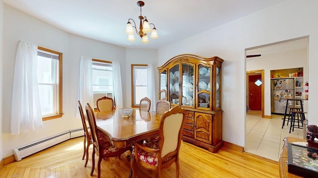dining space featuring a baseboard radiator, plenty of natural light, a chandelier, and light wood finished floors
