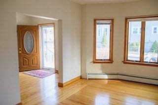 entrance foyer with a baseboard radiator, plenty of natural light, and wood finished floors