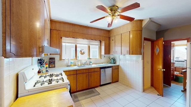 kitchen featuring stainless steel dishwasher, white gas stove, under cabinet range hood, light countertops, and tile walls
