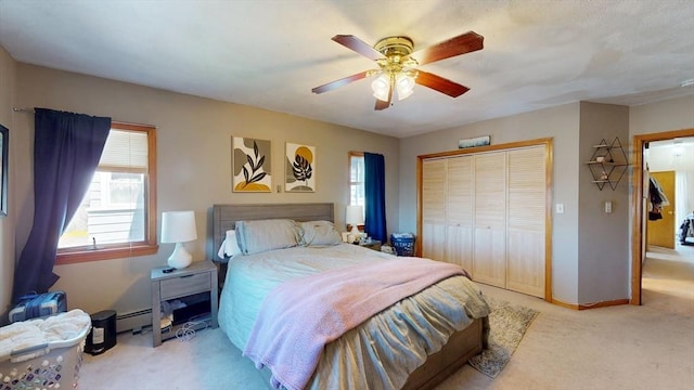 bedroom with carpet, a baseboard heating unit, a closet, a ceiling fan, and baseboards