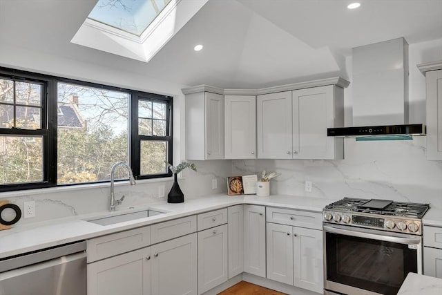 kitchen featuring sink, wall chimney range hood, appliances with stainless steel finishes, and a wealth of natural light