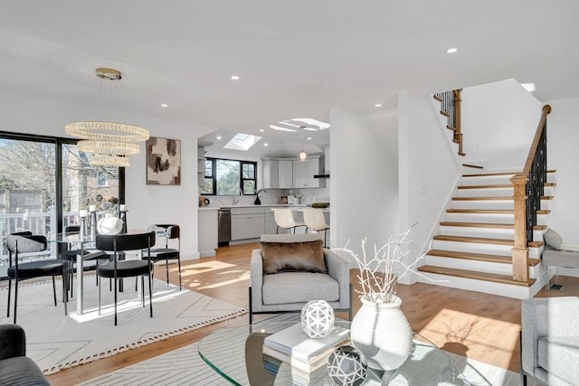 living room featuring an inviting chandelier, a skylight, and light hardwood / wood-style floors