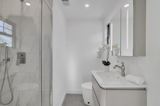 bathroom featuring toilet, vanity, tile patterned flooring, and tiled shower