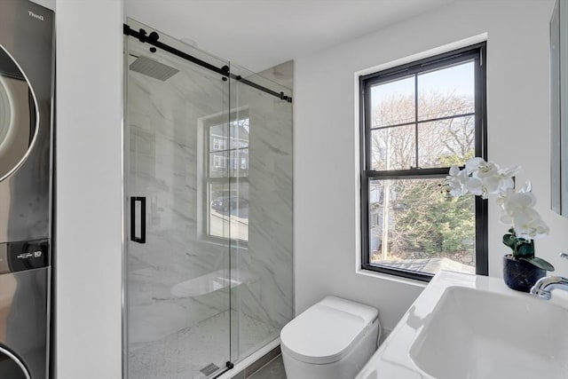 bathroom with toilet, stacked washer / dryer, a shower with shower door, and sink