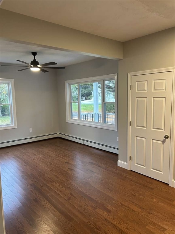 empty room featuring baseboard heating, ceiling fan, and dark hardwood / wood-style floors