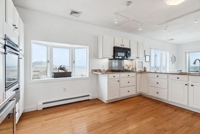 kitchen with baseboard heating, a sink, black appliances, and white cabinetry