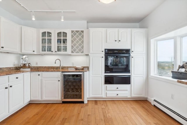 kitchen featuring wine cooler, baseboard heating, oven, a warming drawer, and rail lighting