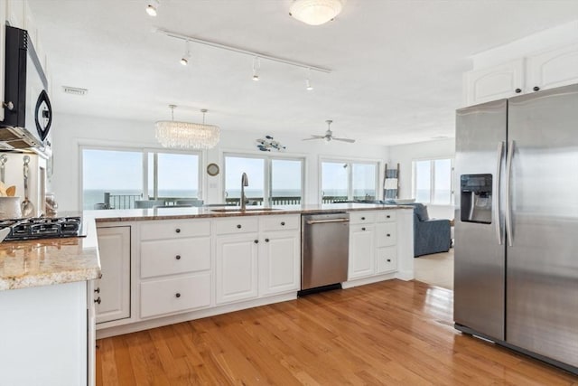 kitchen featuring appliances with stainless steel finishes, a sink, white cabinetry, and open floor plan
