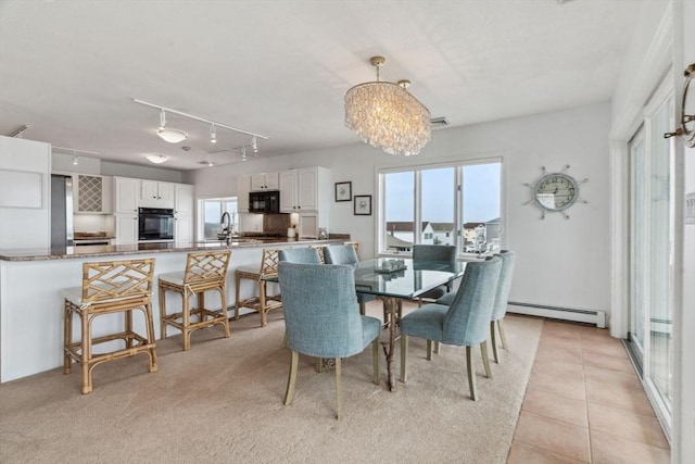 dining room with a baseboard radiator, plenty of natural light, a chandelier, and light tile patterned flooring