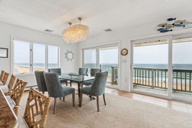 dining room with a chandelier, light tile patterned floors, a water view, light carpet, and a baseboard radiator