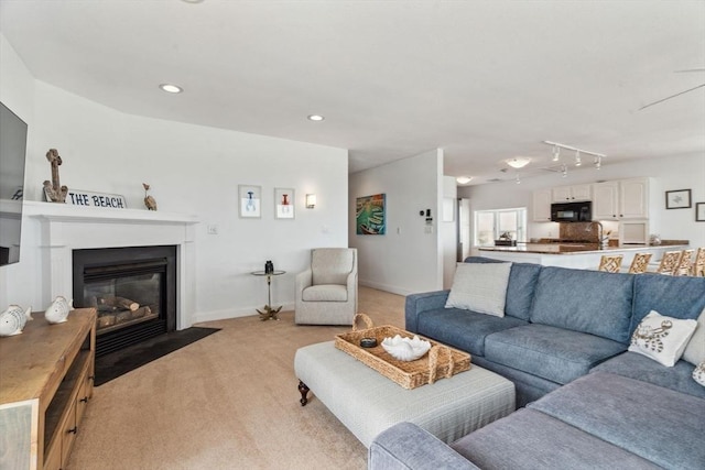 living area featuring light carpet, a fireplace with flush hearth, recessed lighting, and baseboards