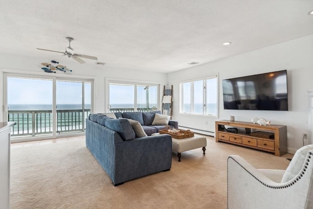 living area with a baseboard radiator, light colored carpet, a ceiling fan, a water view, and recessed lighting