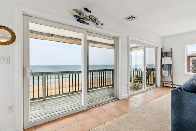 sunroom / solarium with a baseboard radiator, tile patterned flooring, a water view, and baseboards