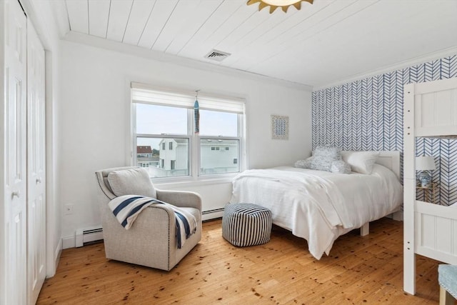 bedroom with wallpapered walls, a baseboard heating unit, ornamental molding, light wood-type flooring, and an accent wall