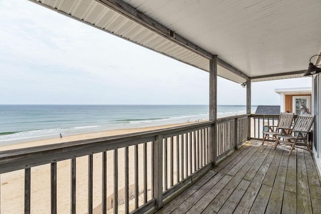 wooden deck with view of water and beach