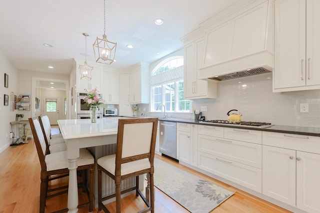 kitchen with stainless steel appliances, a kitchen bar, backsplash, white cabinets, and recessed lighting