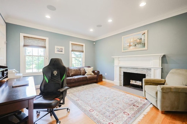 office area featuring crown molding, light wood-type flooring, recessed lighting, a stone fireplace, and baseboards