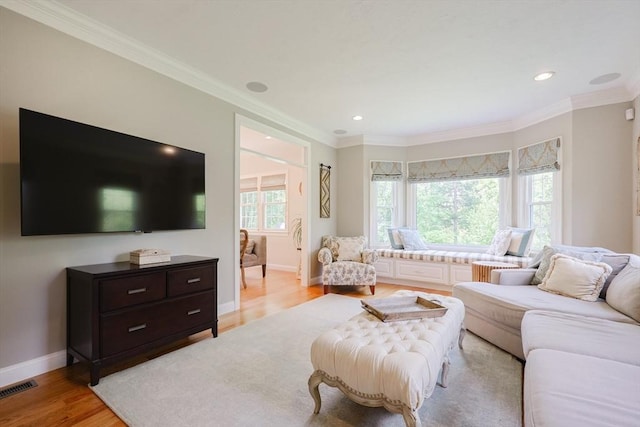living area with light wood-type flooring, crown molding, baseboards, and recessed lighting