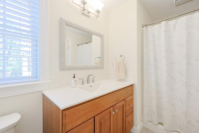 bathroom featuring toilet, vanity, and a shower with shower curtain