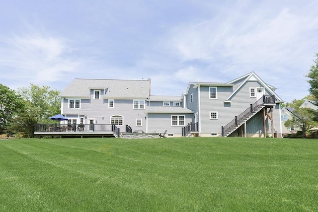 back of property with a deck, a yard, and stairs