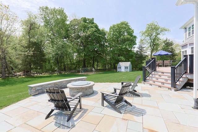 view of patio / terrace featuring an outdoor fire pit, a wooden deck, a shed, an outbuilding, and stairway