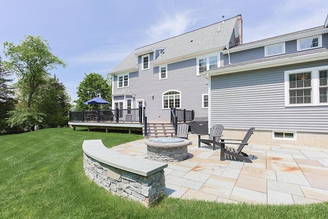 back of house featuring a fire pit, a patio, a deck, a lawn, and roof with shingles