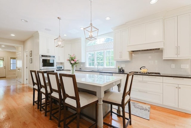 kitchen featuring stainless steel appliances, a breakfast bar, white cabinetry, and recessed lighting